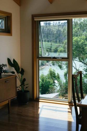 a room with a large window and a table and chair at Modern Waterfront House at Susans Bay, Primrose in Primrose Sands