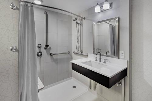 uma casa de banho branca com um lavatório e um chuveiro em Sheraton Syracuse University Hotel and Conference Center em Syracuse