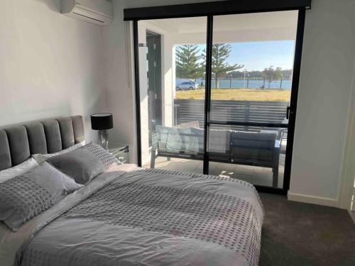 a bedroom with a bed and a large glass window at New ground floor 2 bed/2 bath Apartment Marina in Mandurah