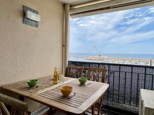 - une table en bois sur un balcon avec vue sur la plage dans l'établissement Studio 4 pers, 150m Mer, Clim, Terrasse, Parking, Ascenseur - Argelès-sur-Mer - FR-1-225-783, à Argelès-sur-Mer
