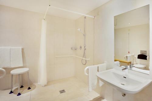 a white bathroom with a sink and a shower at Holiday Inn Nürnberg City Centre by IHG in Nürnberg