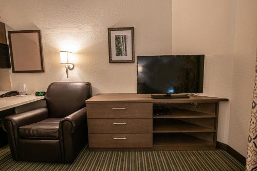 a hotel room with a desk with a television and a chair at Candlewood Suites-West Springfield by IHG in West Springfield