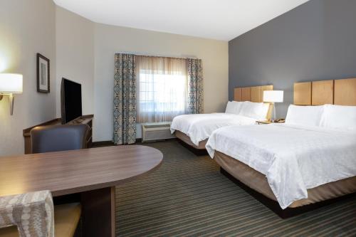 a hotel room with two beds and a desk at Candlewood Suites-West Springfield, an IHG Hotel in West Springfield