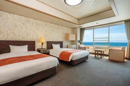 a hotel room with two beds and a large window at Hotel New Akao in Atami