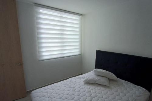 a white bedroom with a bed and a window at Apto con vista panoramica al nevado del ruiz y del tolima in Ricaurte