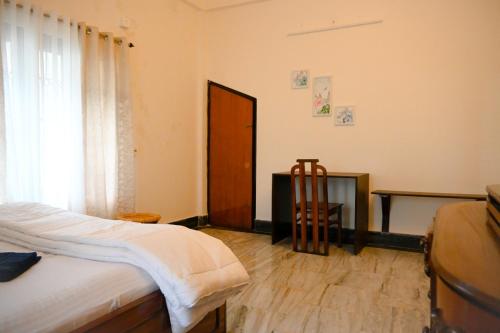 a bedroom with a bed and a table and a window at Bhaskar Homestay - The Bungalow in Dibrugarh