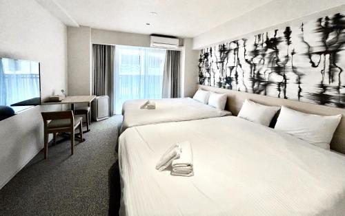 大阪市にあるApartment Hotel 11 Nambaのベッド2台とデスクが備わるホテルルームです。