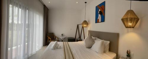 a bedroom with a bed with white sheets and a window at Dreamers Farm in Vinh Thanh