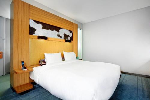 a bedroom with a large white bed with a wooden headboard at Aloft Bolingbrook in Bolingbrook