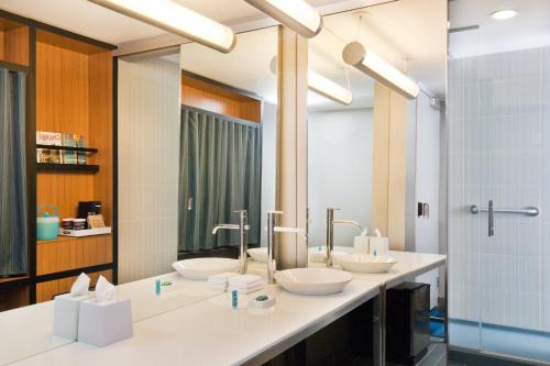 a bathroom with three sinks and a large mirror at Aloft Bolingbrook in Bolingbrook