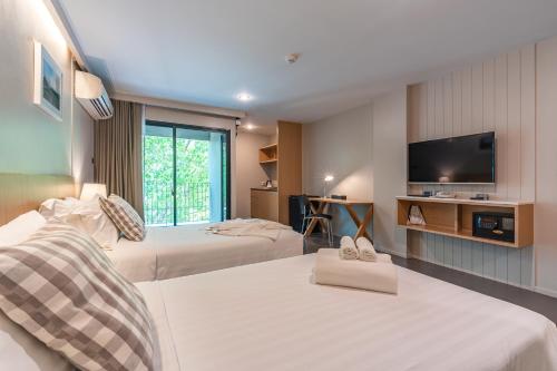 a hotel room with two beds and a flat screen tv at Naga Residence in Bangkok