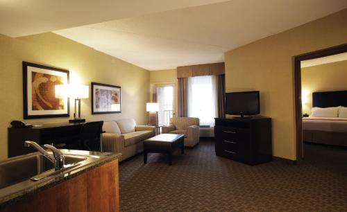 a hotel room with a couch and a bed and a television at Holiday Inn Phoenix/Chandler by IHG in Chandler