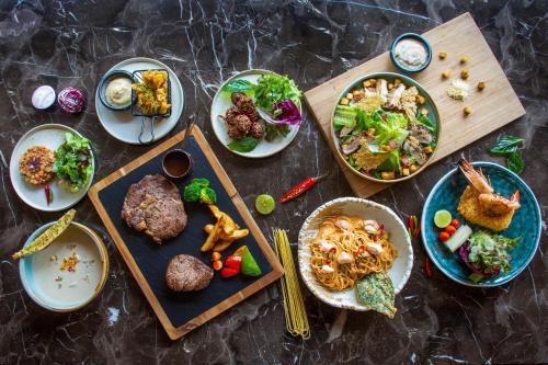 a table topped with plates of food and bowls of food at Grand Richmond Stylish Convention Hotel in Nonthaburi