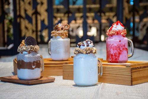 three milkshakes sitting on wooden plates on a table at Grand Richmond Stylish Convention Hotel in Nonthaburi