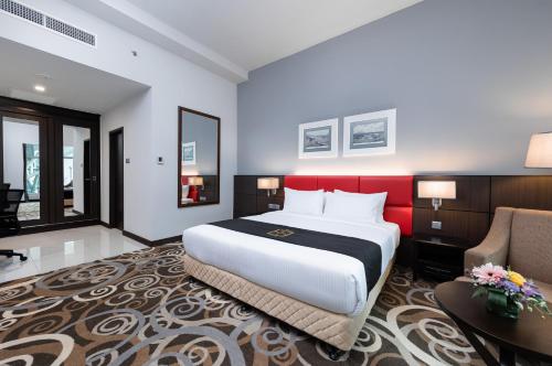 a hotel room with a large bed and a chair at Raia Hotel & Convention Centre Kuching in Kuching