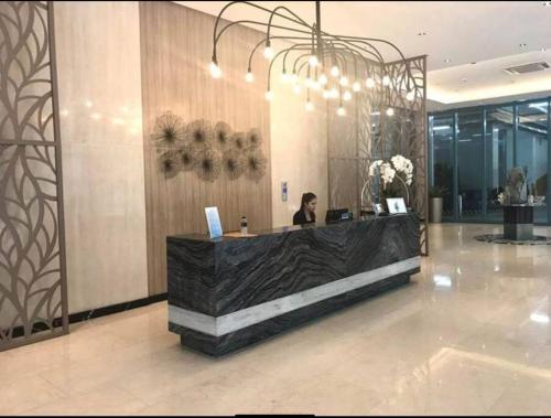 a woman sitting at a reception desk in a lobby at One Uptown Residence Prime Loc BGC,Uptown Linked 1BR,Washer,200mbps in Manila