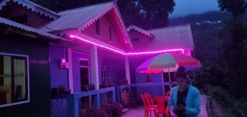 a woman walking in front of a house with pink lights at Mamring Home stay - Philamon Mukhia in Darjeeling