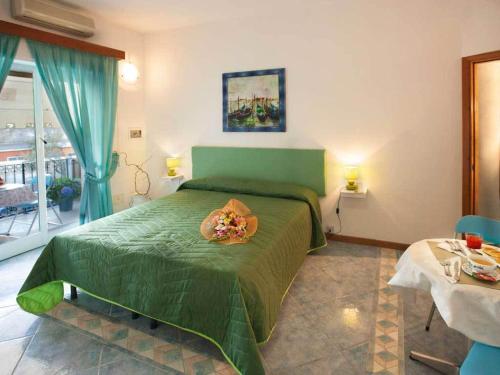 Un dormitorio con una cama verde y una mesa en La Brezza B&B Ischia, en Isquia