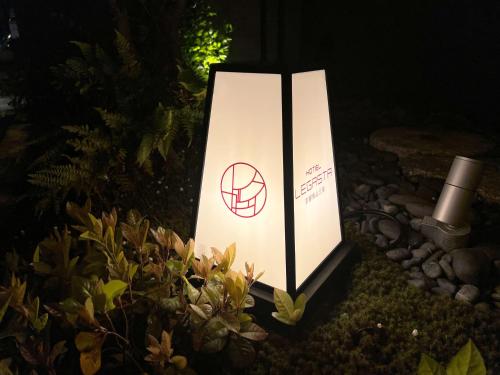 a lighted sign sitting next to a bush at Hotel Legasta Kyoto Higashiyama Sanjo in Kyoto