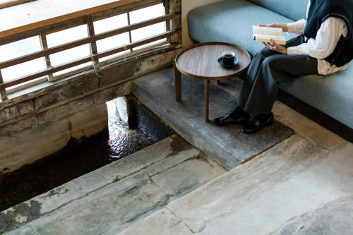 a person sitting on a couch reading a book next to a table at Hotel mio in Shimabara