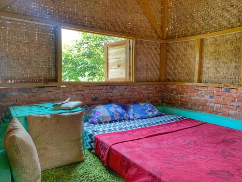 Ce lit se trouve dans une chambre dotée d'un mur en briques. dans l'établissement Farmstay Manangel, à Sindanglaka
