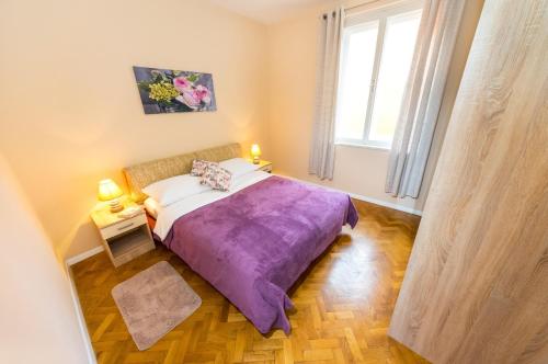 1 dormitorio con 1 cama con manta morada en Apartment Colona, en Zadar