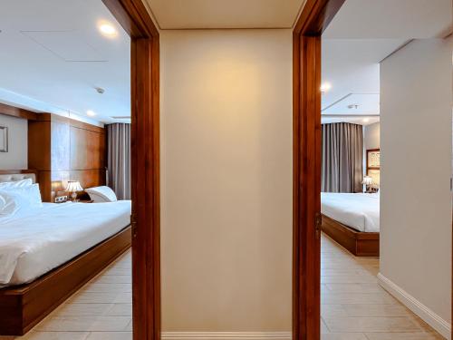 a bedroom with two beds and a mirror at Paris Deli Danang Beach Hotel in Da Nang