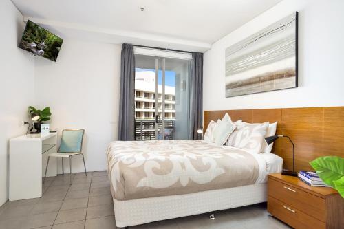 a bedroom with a bed and a desk and a window at 2BR Stylish Getaway @ Harbour Lights Cairns in Cairns