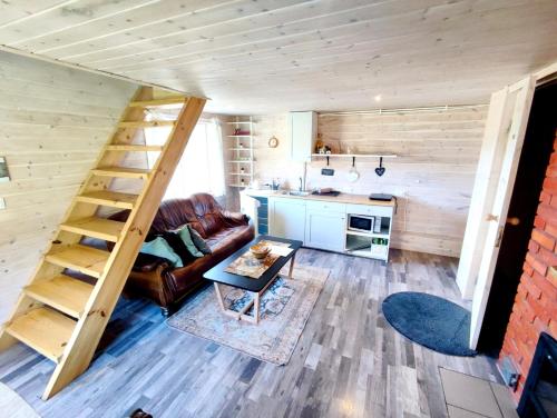 uma sala de estar com uma escada numa pequena casa em Charming Sauna Cottage in a Horse Ranch em Lieplaukė