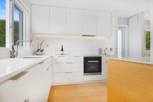 uma cozinha branca com armários brancos e um lavatório em Family-Friendly, Airport 6 mins, Spacious with Garden em Christchurch