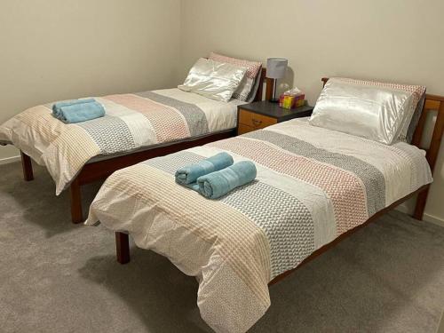 two beds with towels on them in a room at Refurbished Family Home in Glen Waverley