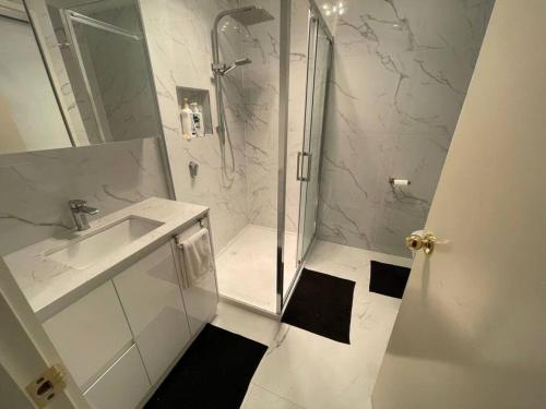 a white bathroom with a shower and a sink at Refurbished Family Home in Glen Waverley