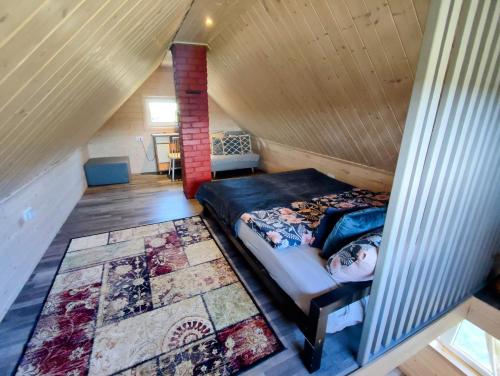 a bedroom with a bed in a wooden attic at Charming Sauna Cottage in a Horse Ranch in Lieplaukė