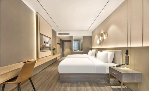 Orange Hotel - Taicang Nanyang Plaza في Taicang: غرفة نوم مع سرير أبيض كبير ومكتب