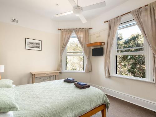a bedroom with a bed and two windows at Lord Wolseley Hotel in Sydney