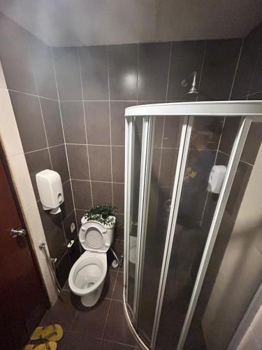 a bathroom with a toilet and a shower with a plant at Cameron Iris AiSHomestay in Tanah Rata