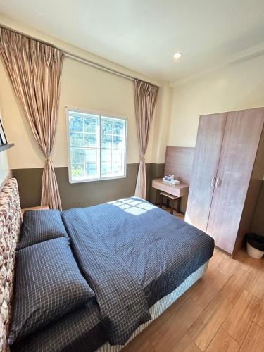 a bedroom with a bed and a dresser and a window at Cameron Iris AiSHomestay in Tanah Rata