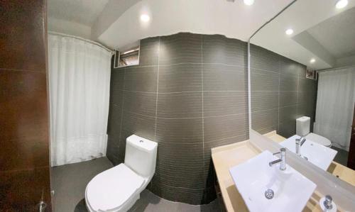 uma casa de banho com um WC, um lavatório e um espelho. em Departamento Las Condes Mall Sport em Santiago