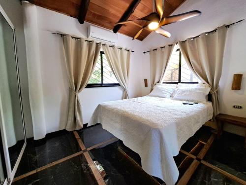 a bedroom with a bed and two windows at Casa Namaste del Pacifico - Luxury Villa in Santa Teresa Beach