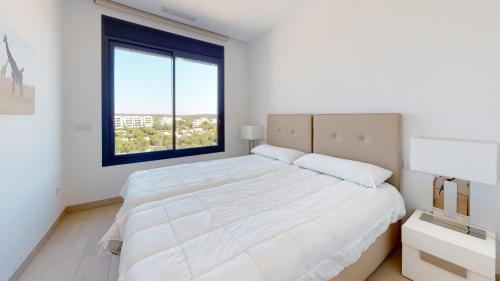 - une chambre blanche avec un grand lit et une fenêtre dans l'établissement Las Colinas Golf, luxury penthouse, à Orihuela