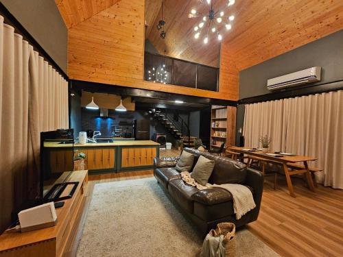 a living room with a leather couch and a kitchen at Take Time Nature Resort in Ban Tha Sai