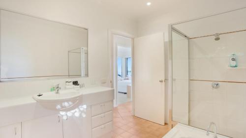a white bathroom with a sink and a shower at Sapphire Views in Merimbula
