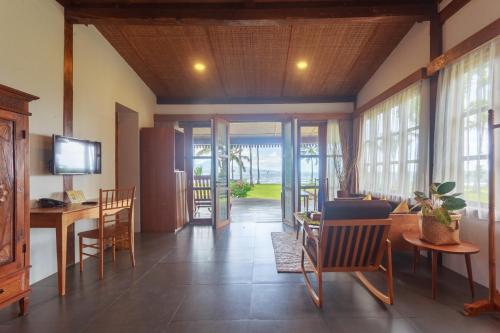 a living room with a table and chairs and windows at Villa So Long Banyuwangi - Ijen in Banyuwangi