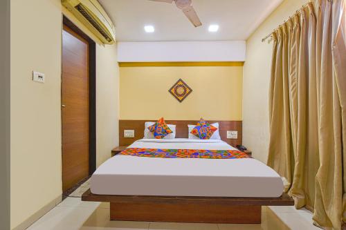 a bedroom with a large bed and a wooden door at FabHotel RB Residency in Surat
