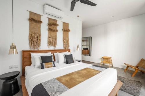 ein Schlafzimmer mit einem großen weißen Bett und einem Stuhl in der Unterkunft Stylish 3BR Villa Myla By OriVista, Pool-Netflix-Wifi in Canggu