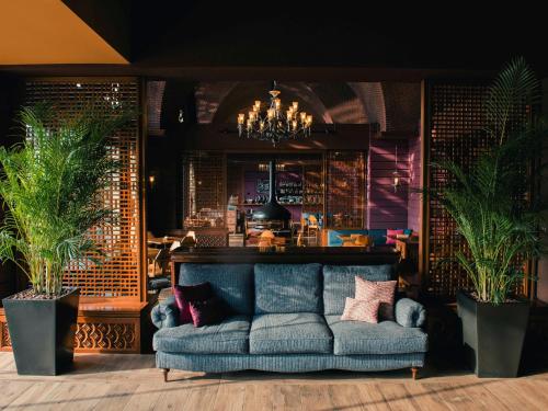 a living room with a blue couch and plants at The Luigans Spa and Resort in Fukuoka