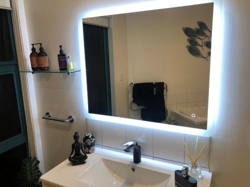 a bathroom with a sink and a large mirror at Luxury Waterfront in One Tree Point