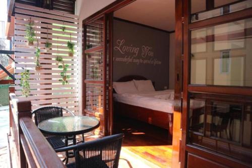 a balcony with a bed and a table and chairs at DaViKa Hotel in Vientiane