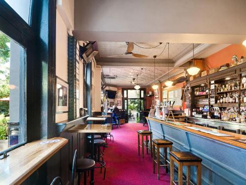 a bar with tables and stools in a restaurant at Lord Wolseley Hotel in Sydney