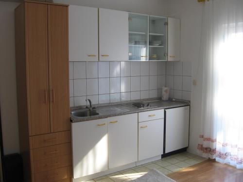 eine Küche mit weißen Schränken und einem Waschbecken in der Unterkunft Apartments Marjanovic in Bol